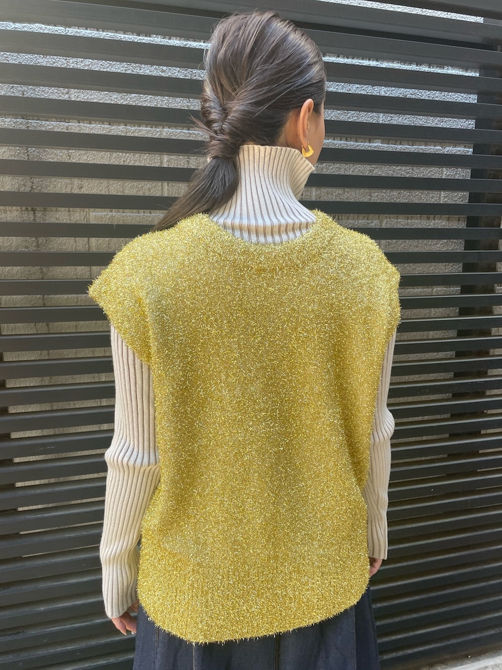 ブルー系のデニムスカート、ホワイト系のニット/セーター、ゴールド系のベストを着用したレディースの冬コーディネートの8枚目の写真