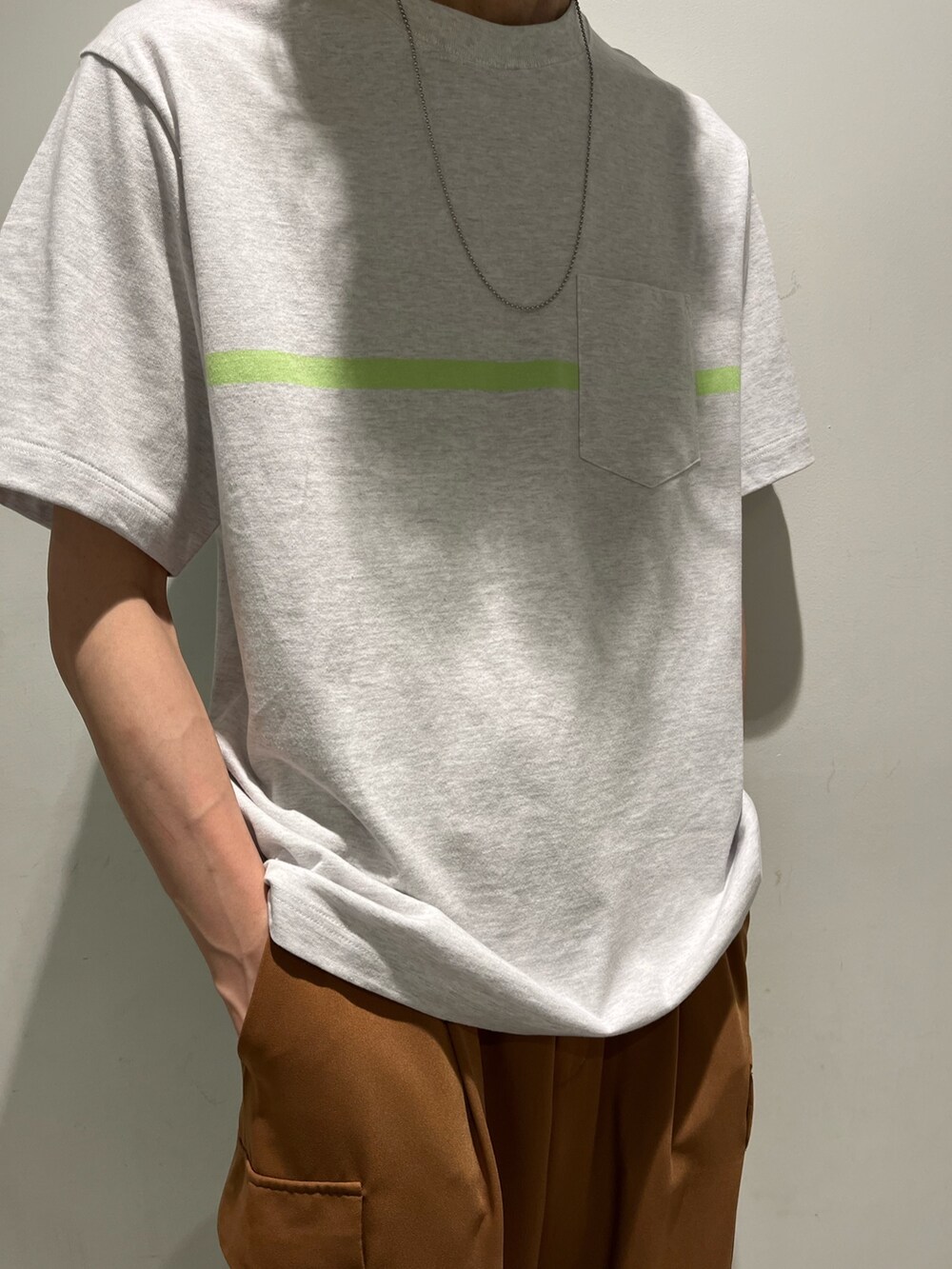 ホワイト系のトップス、ブラウン系のカーゴパンツ、シルバー系のネックレスを着用したメンズの夏コーディネートの2枚目の写真