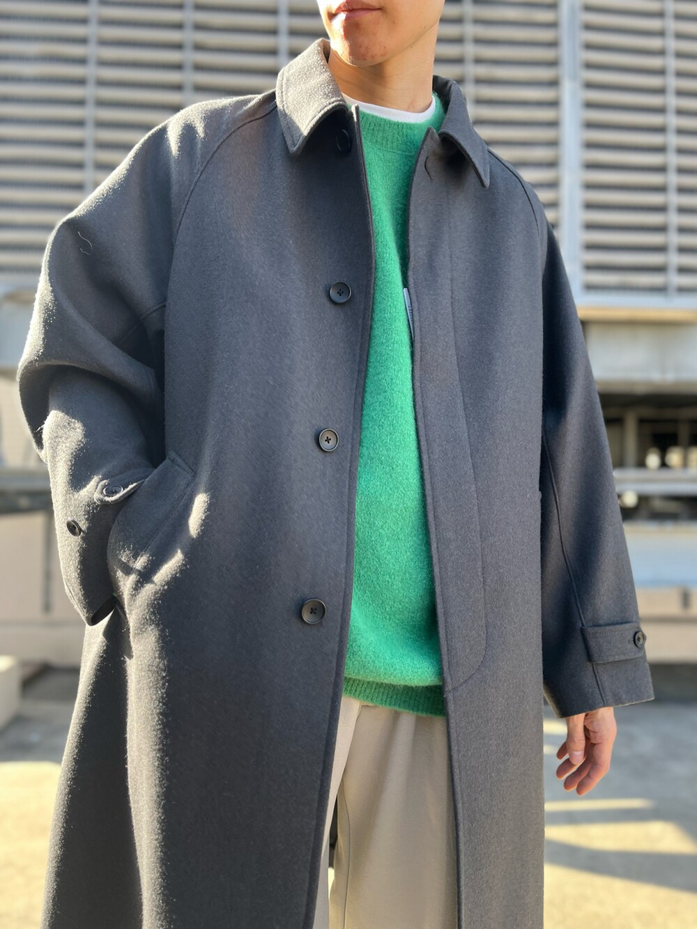 ベージュ系のその他パンツ、グレー系のステンカラーコート、グリーン系のニット/セーターを着用したメンズの冬コーディネートの2枚目の写真