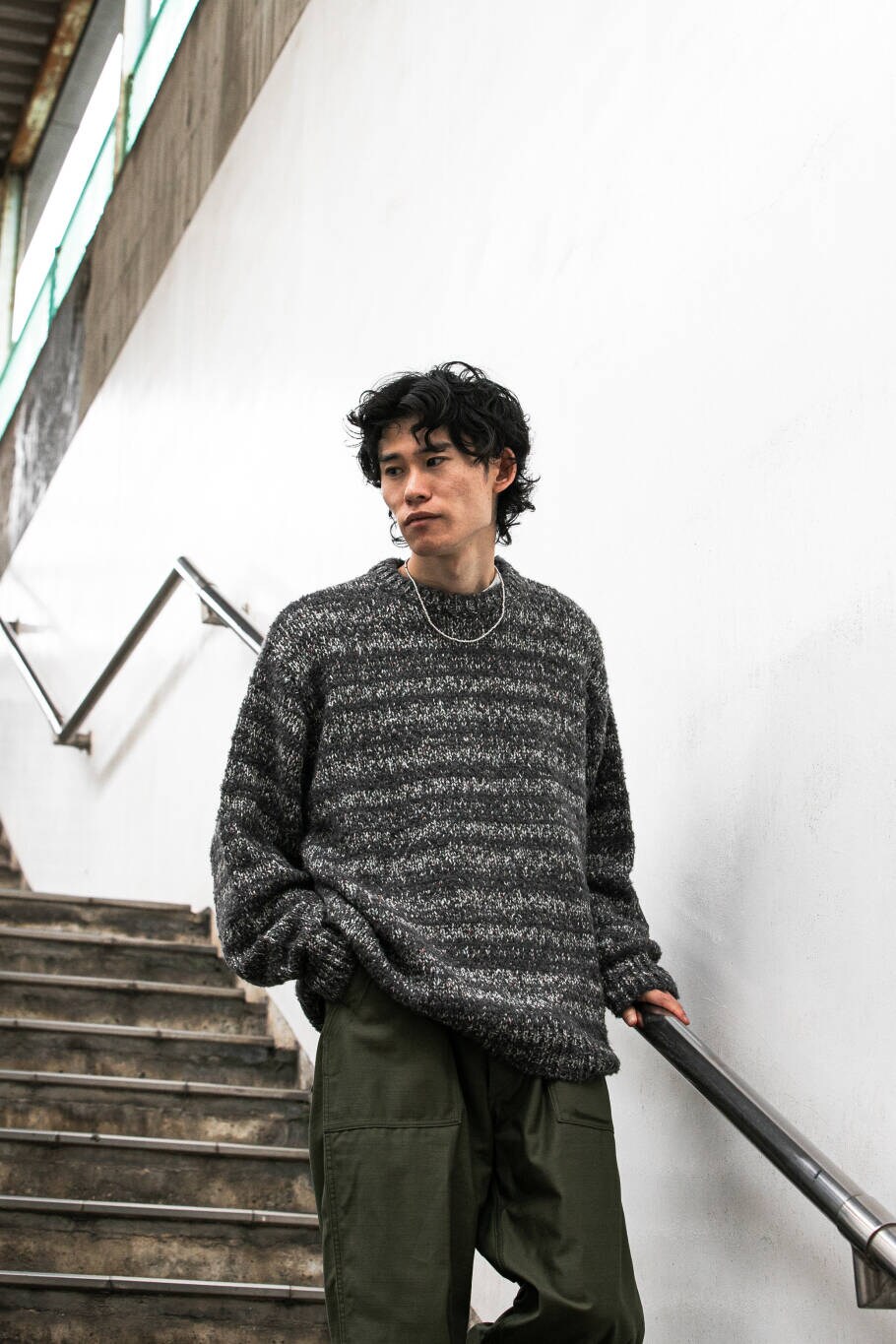 グレー系のニット/セーター、グリーン系のチノパンツを着用したメンズの秋コーディネートの2枚目の写真