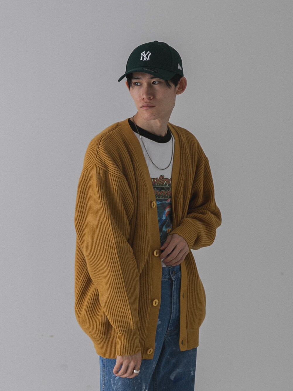 ゴールド系のカーディガン/ボレロ、ブラック系のTシャツ/カットソー、ブルー系のデニムパンツを着用したメンズの秋コーディネートの2枚目の写真