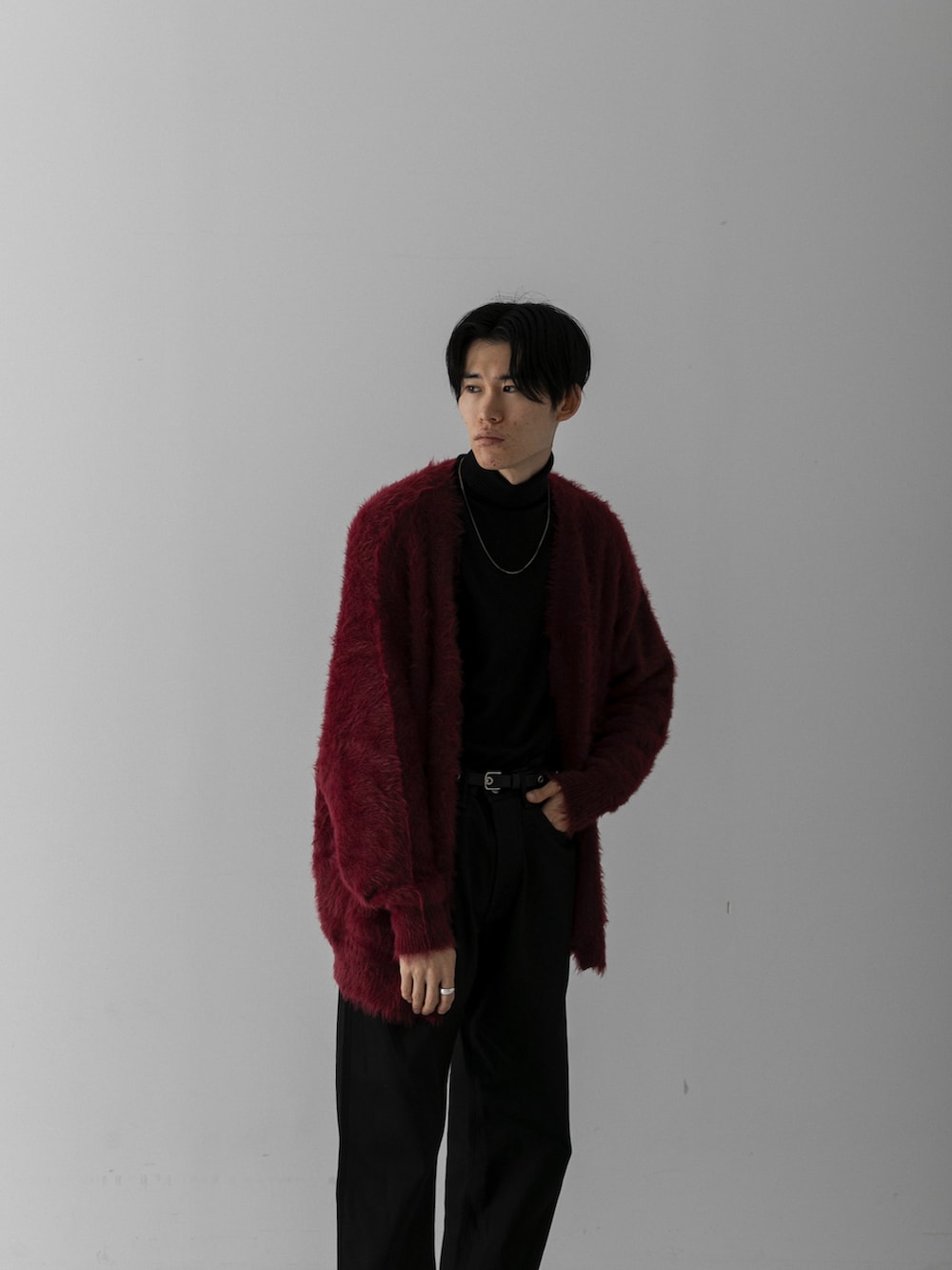 ブラック系のスラックス、レッド系のカーディガン/ボレロ、ホワイト系のニット/セーターを着用したメンズの冬コーディネートの3枚目の写真