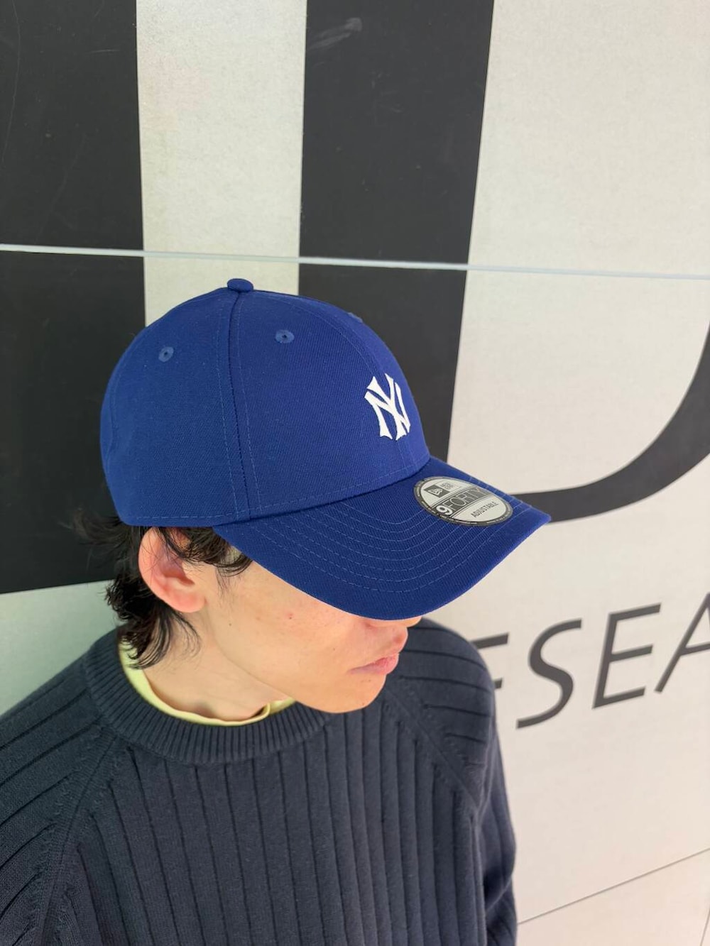 グレー系のその他パンツ、ブルー系のニット/セーター、ブルー系のキャップを着用したメンズの冬コーディネートの3枚目の写真