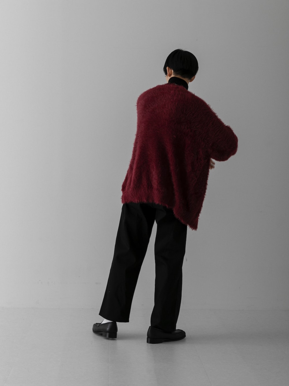 ブラック系のスラックス、レッド系のカーディガン/ボレロ、ホワイト系のニット/セーターを着用したメンズの冬コーディネートの2枚目の写真