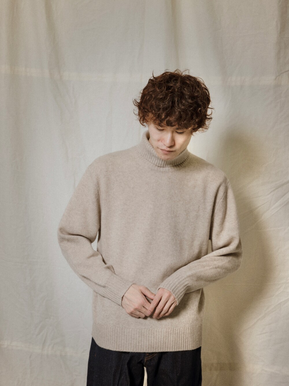 ブルー系のデニムパンツ、ベージュ系のニット/セーターを着用したメンズの冬コーディネートの2枚目の写真