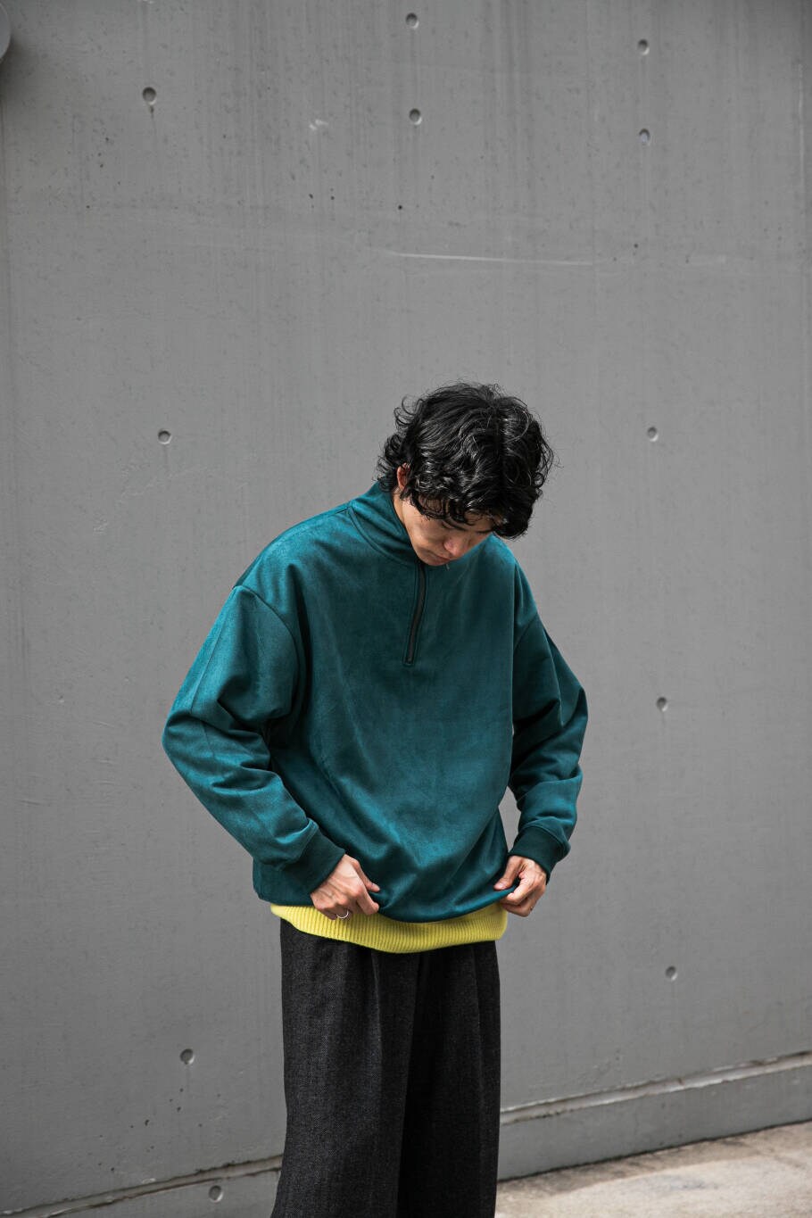 イエロー系のニット/セーター、グリーン系のTシャツ/カットソー、グレー系のスラックスを着用したメンズの冬コーディネートの3枚目の写真