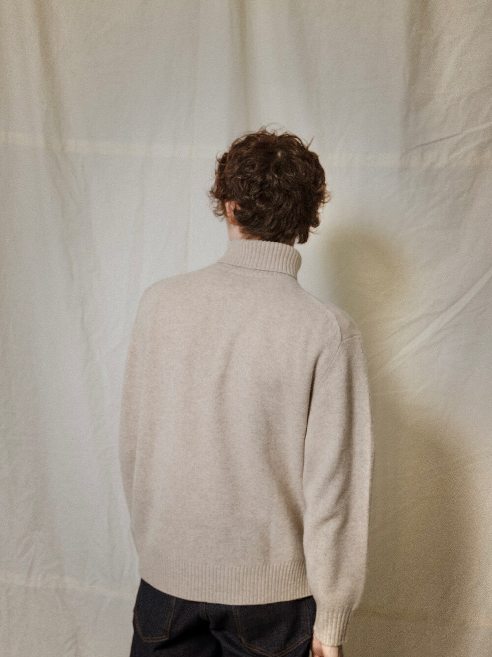 ブルー系のデニムパンツ、ベージュ系のニット/セーターを着用したメンズの冬コーディネートの3枚目の写真