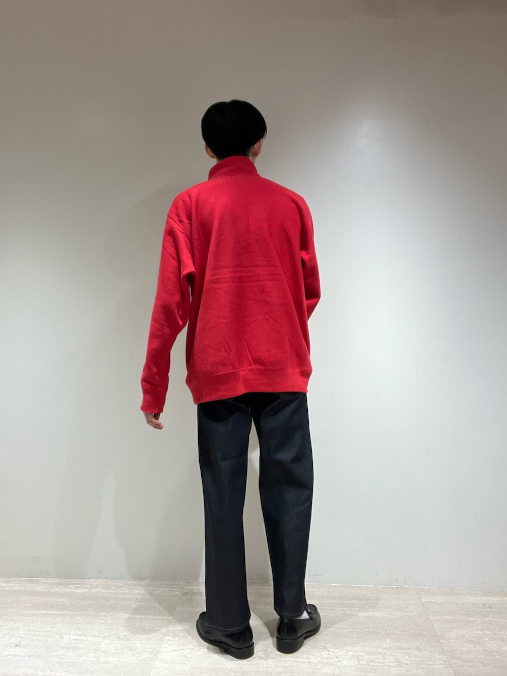 ブラック系のローファー、ブルー系のデニムパンツ、レッド系のスウェットを着用したメンズの秋コーディネートの2枚目の写真