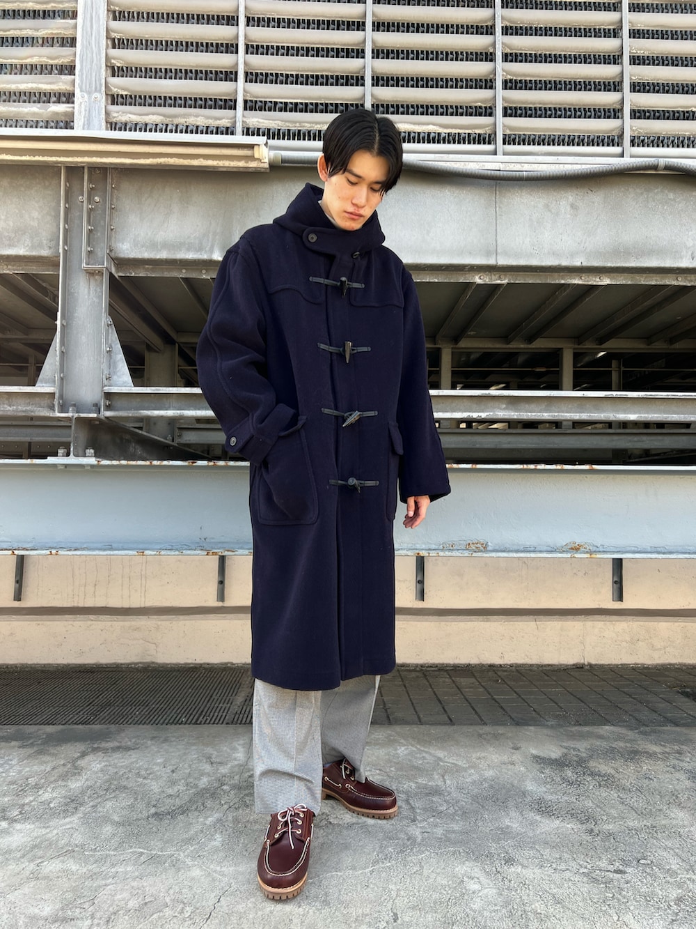 ブラウン系のモカシン/デッキシューズ、ブルー系のダッフルコート、オレンジ系のカーディガン/ボレロを着用したメンズの秋コーディネートの2枚目の写真