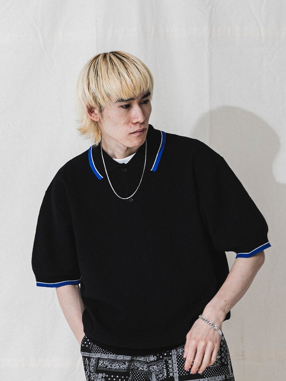 ベージュ系のポロシャツ、シルバー系のネックレスを着用したメンズの春コーディネートの2枚目の写真