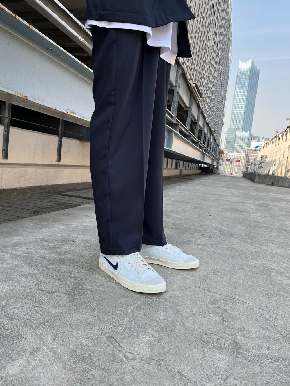 ブルー系のノーカラージャケット、ホワイト系のスニーカー、ブルー系のスラックスを着用したメンズの春コーディネートの2枚目の写真