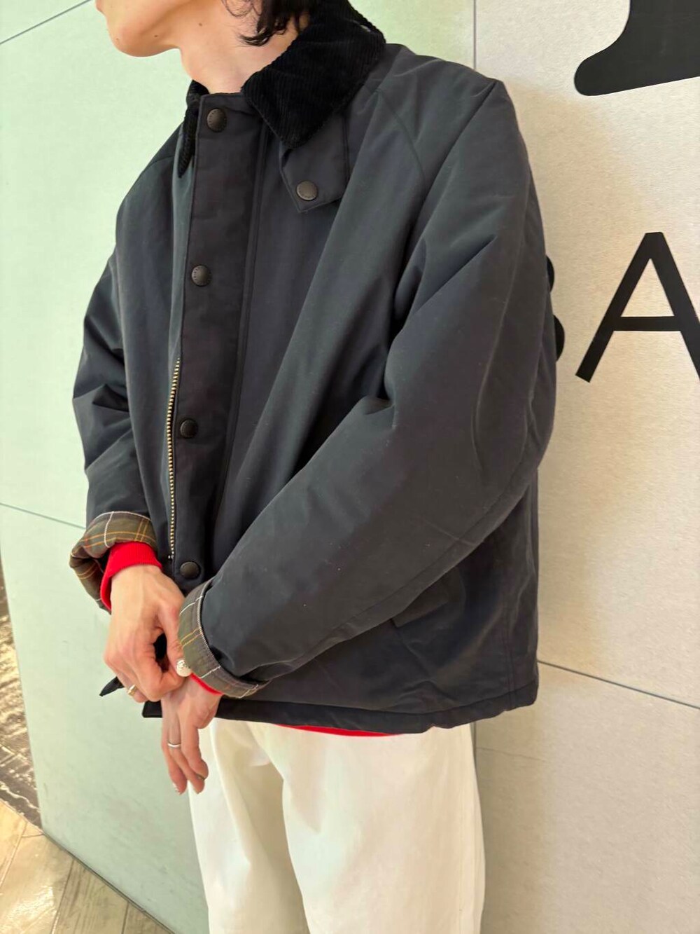 レッド系のスウェット、ホワイト系のデニムパンツ、ブラック系のダウンジャケット/コートを着用したメンズの冬コーディネートの2枚目の写真