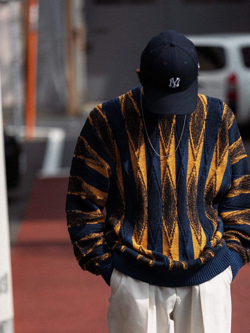 グリーン系のニット/セーター、パープル系のキャップ、シルバー系のネックレスを着用したメンズの冬コーディネートの3枚目の写真