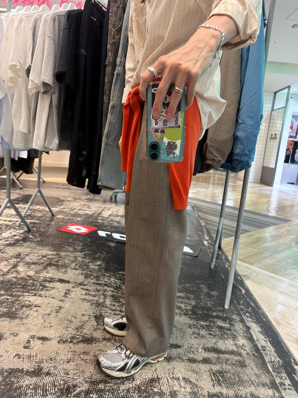 シルバー系のスニーカー、ブラウン系のその他パンツ、オレンジ系のニット/セーターを着用したメンズの春コーディネートの3枚目の写真