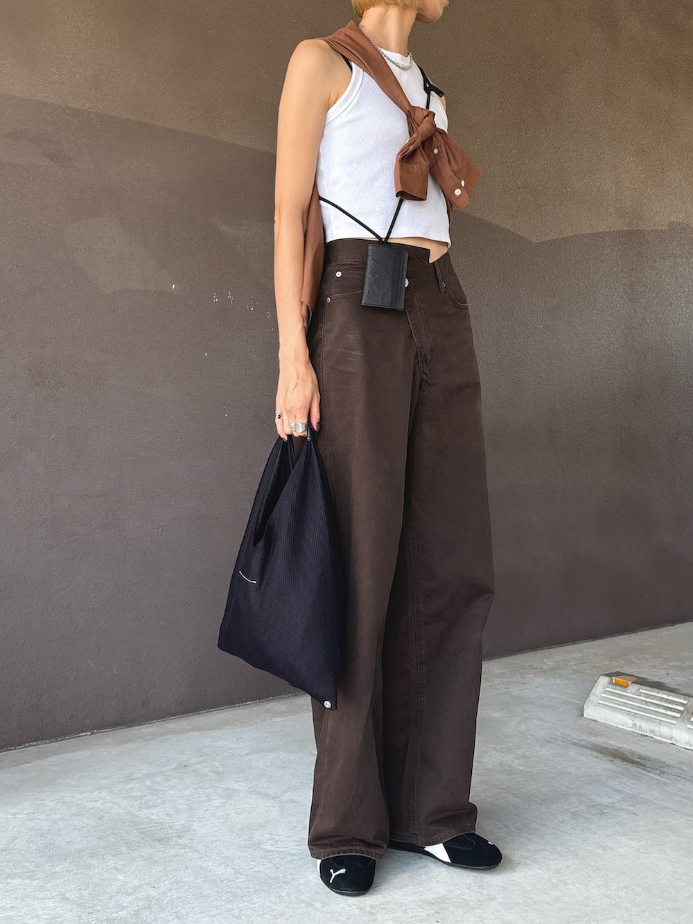 ブラック系のハンドバッグ、ブラック系のスニーカー、ブラウン系のチノパンツを着用したレディースの秋コーディネートの2枚目の写真