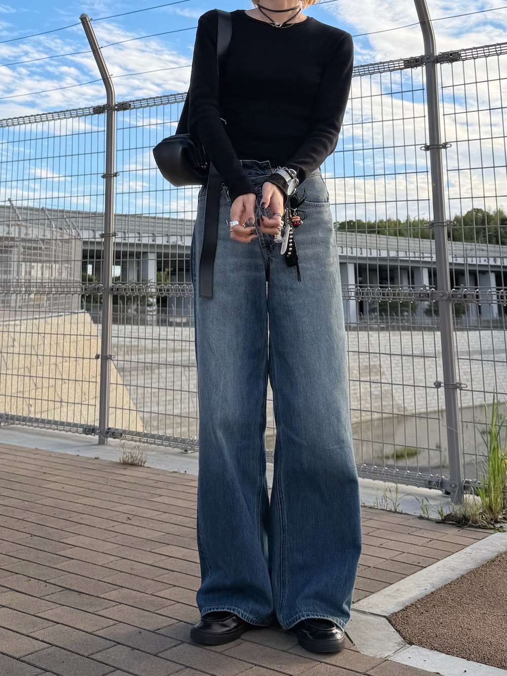 ブルー系のデニムパンツ、ブラック系のローファー、ブラック系のショルダーバッグを着用したレディースの秋コーディネートの2枚目の写真