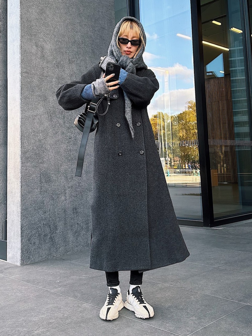 ブラック系のショルダーバッグ、ホワイト系のスニーカー、ブラック系のデニムパンツを着用したレディースの冬コーディネートの2枚目の写真