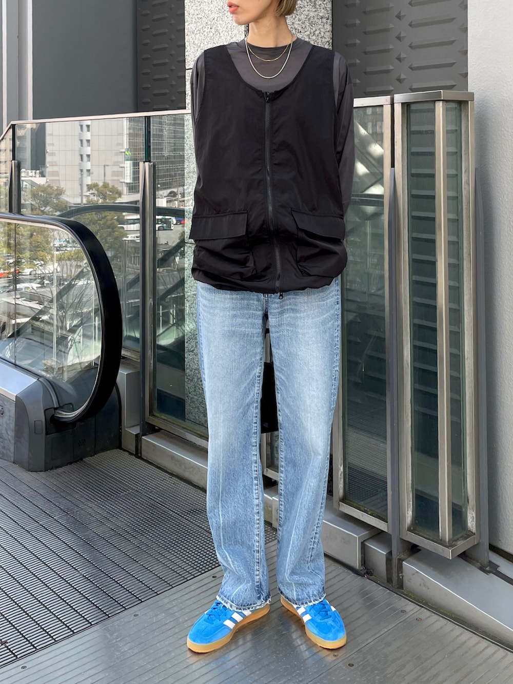 ブルー系のスニーカー、ブルー系のデニムパンツ、ブラック系のワンピースを着用したレディースの春コーディネートの3枚目の写真