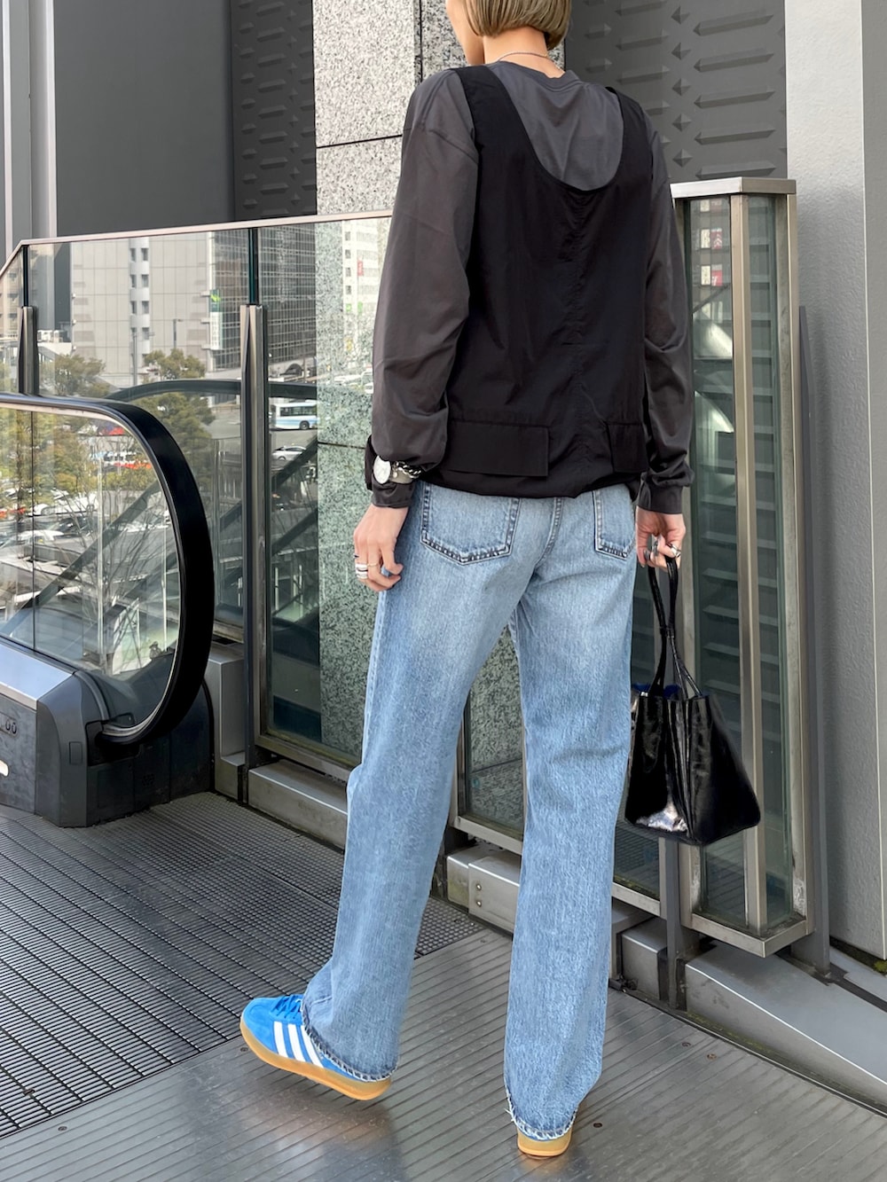 ブルー系のスニーカー、ブルー系のデニムパンツ、ブラック系のワンピースを着用したレディースの春コーディネートの2枚目の写真