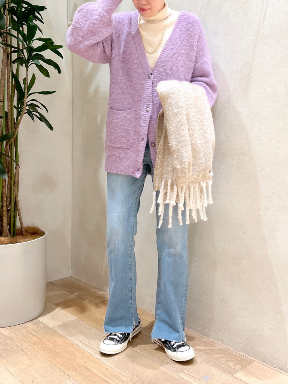 パープル系のカーディガン/ボレロ、ホワイト系のニット/セーター、ブルー系のデニムパンツを着用したレディースの秋コーディネートの2枚目の写真