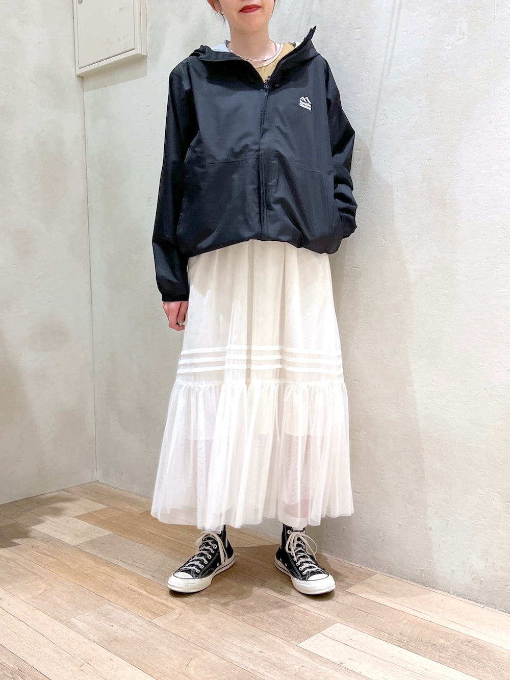 ホワイト系のワンピース、イエロー系のタンクトップ、ブラック系のマウンテンパーカーを着用したレディースの春コーディネートの4枚目の写真