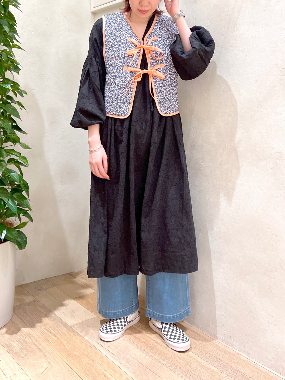 ブラック系のワンピース、ブルー系のデニムパンツ、その他のベストを着用したレディースの春コーディネートの2枚目の写真