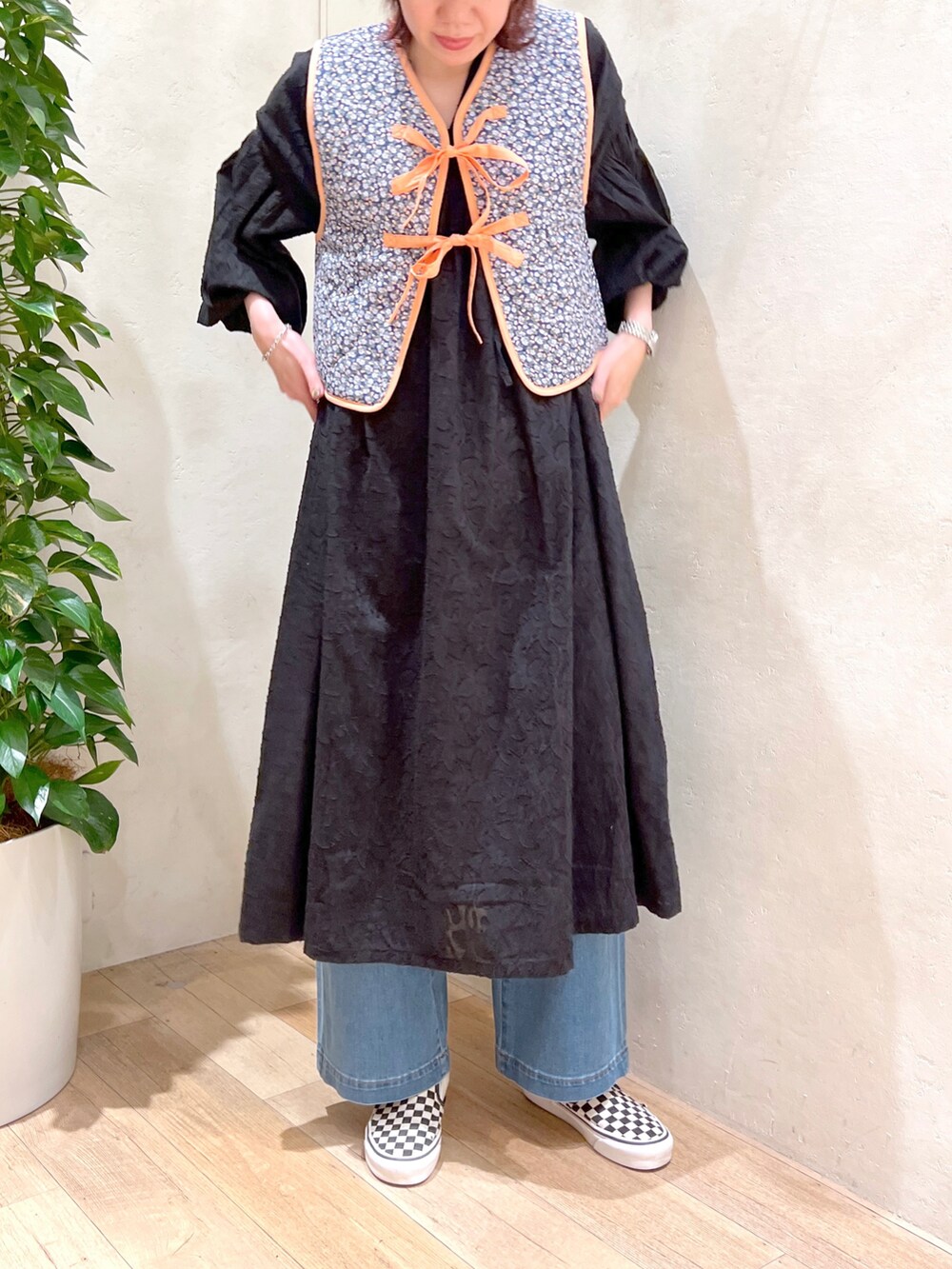 ブラック系のワンピース、ブルー系のデニムパンツ、その他のベストを着用したレディースの春コーディネートの3枚目の写真