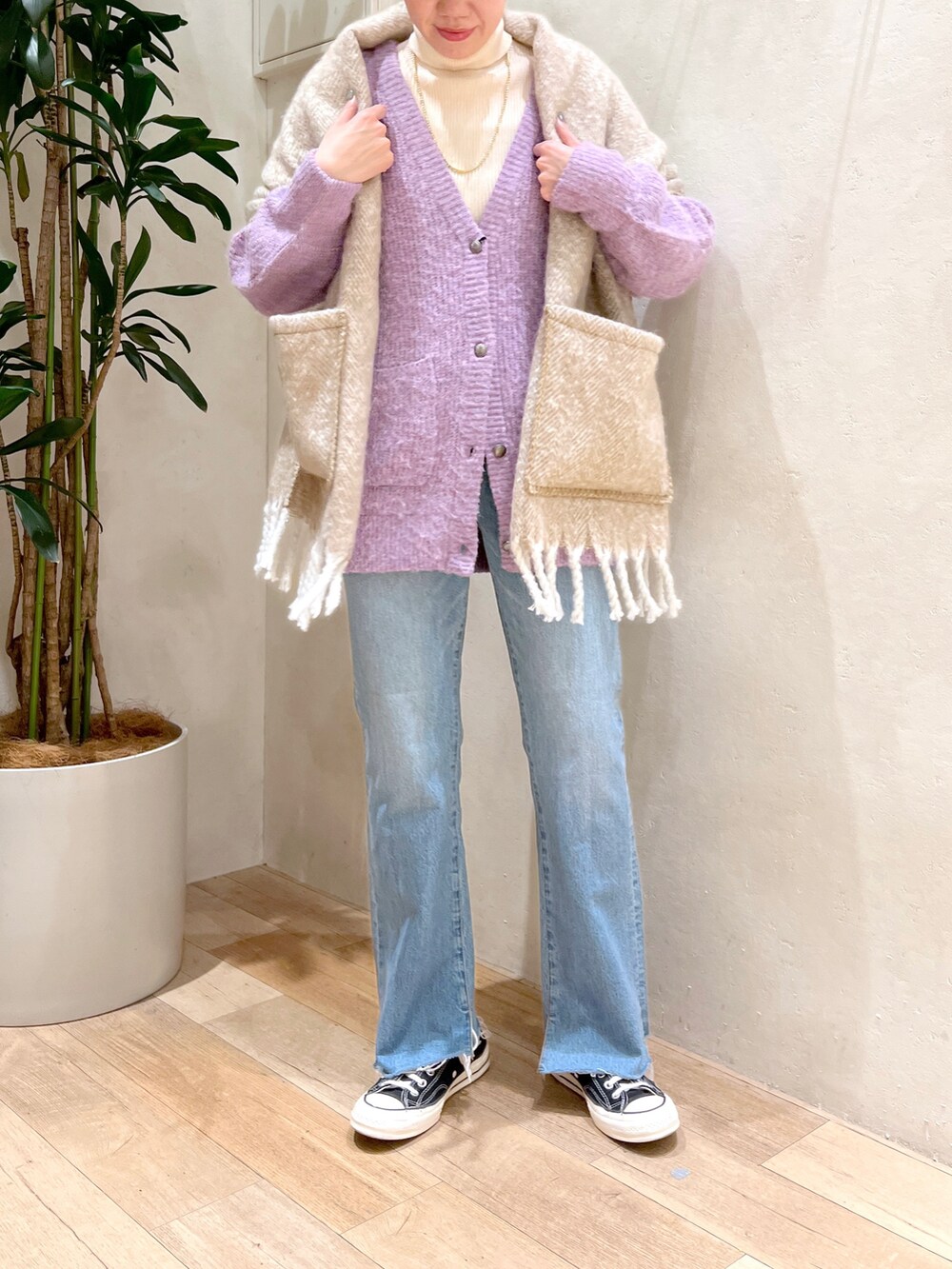 パープル系のカーディガン/ボレロ、ホワイト系のニット/セーター、ブルー系のデニムパンツを着用したレディースの秋コーディネートの3枚目の写真