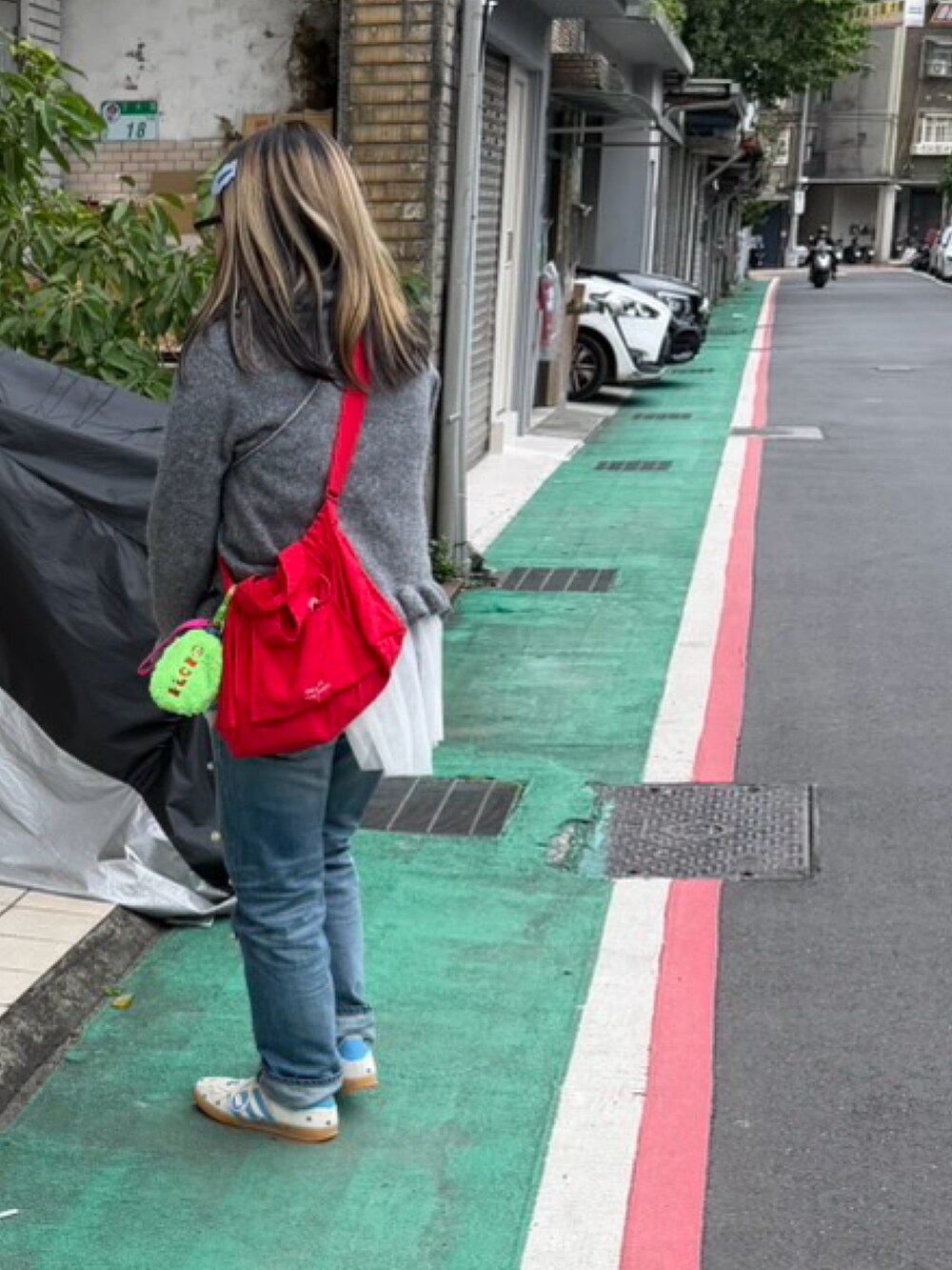レッド系のショルダーバッグ、ブルー系のデニムパンツ、ブルー系のスニーカーを着用したレディースの春コーディネートの2枚目の写真