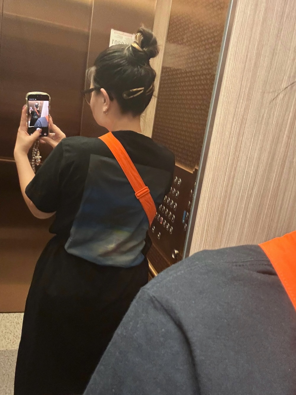 ブラック系のTシャツ/カットソー、オレンジ系のショルダーバッグ、ブラック系のスカートを着用したレディースの夏コーディネートの2枚目の写真
