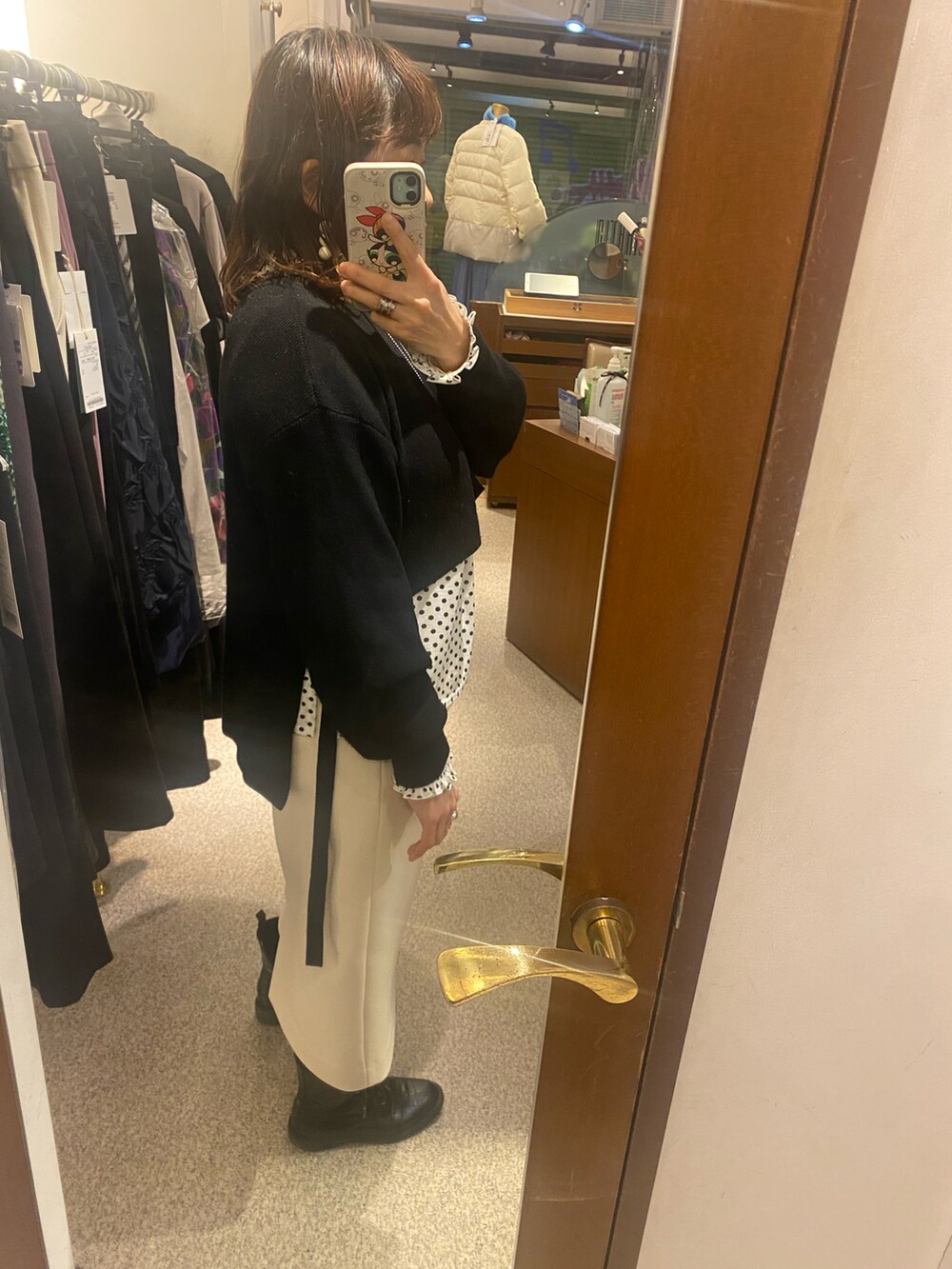 ブラック系のニット/セーター、ホワイト系のTシャツ/カットソー、ホワイト系のスカートを着用したレディースの冬コーディネートの2枚目の写真