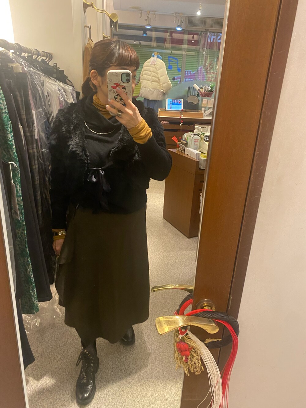 ブラック系のその他アウター、ブラック系のニット/セーター、ブラウン系のスカートを着用したレディースの冬コーディネートの2枚目の写真