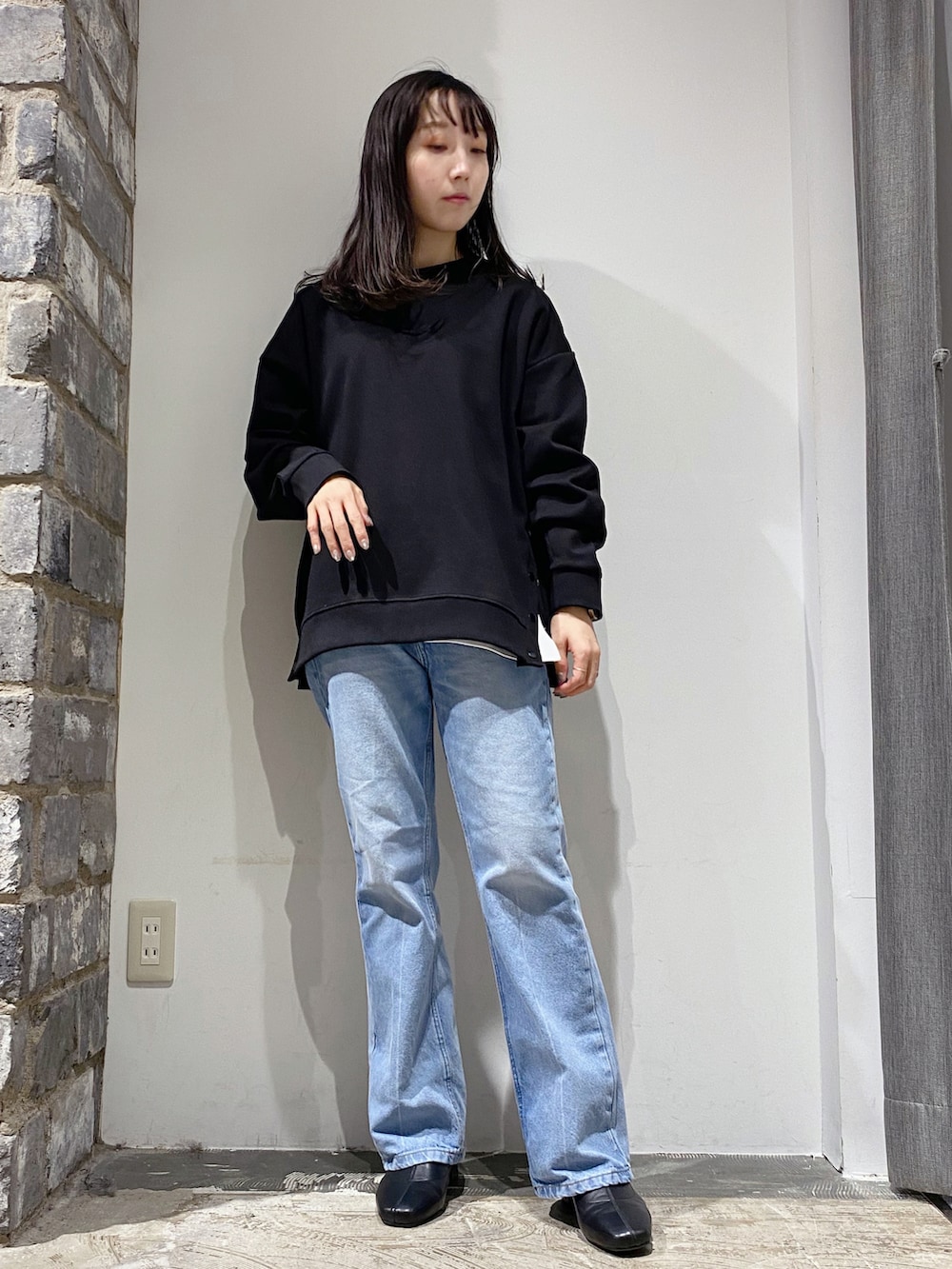 ブラック系のスウェット、ブルー系のデニムパンツ、ブラック系のブーツを着用したレディースの冬コーディネートの2枚目の写真