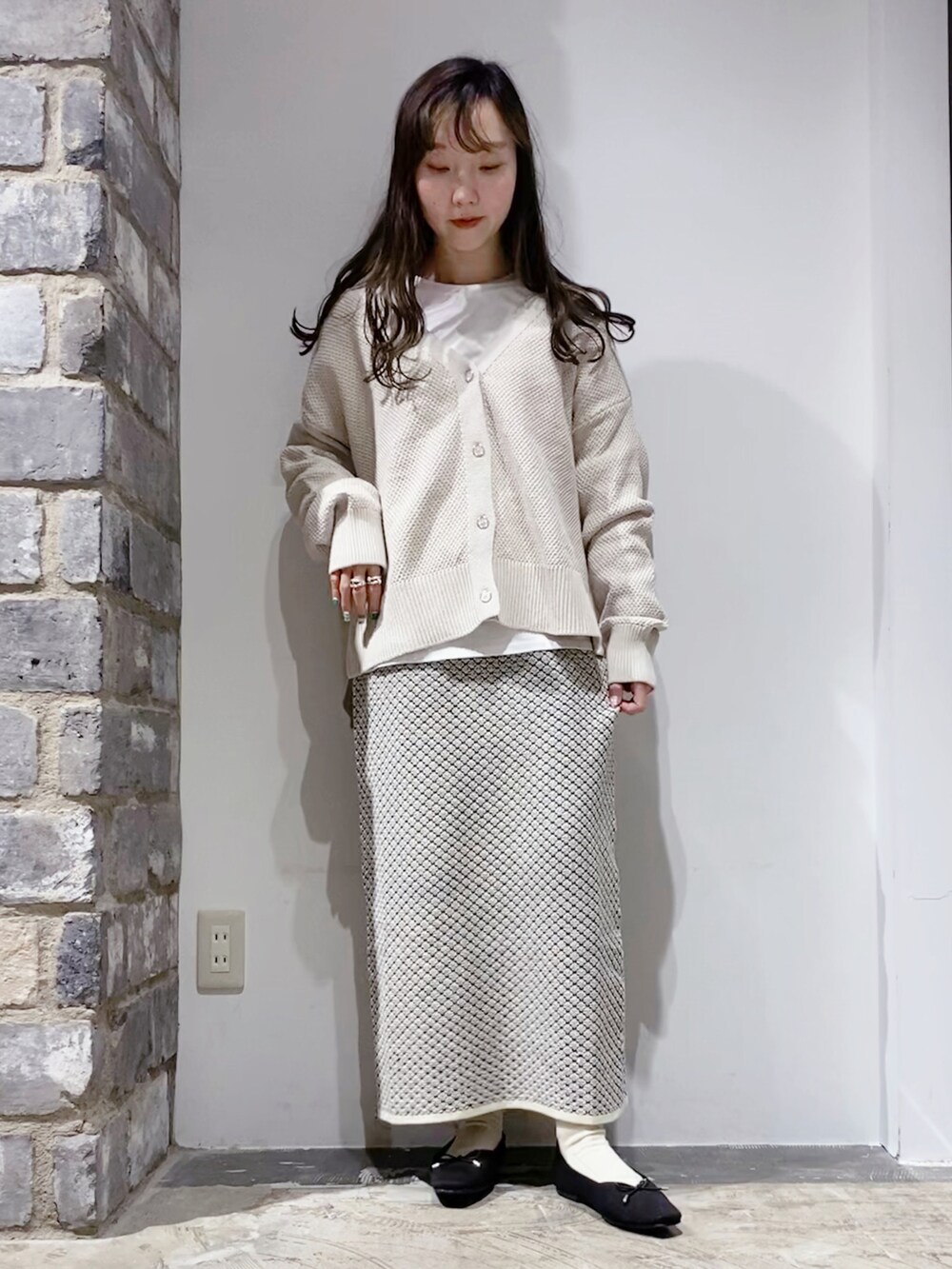 ベージュ系のカーディガン/ボレロ、ホワイト系のスカート、ホワイト系のTシャツ/カットソーを着用したレディースの冬コーディネートの2枚目の写真