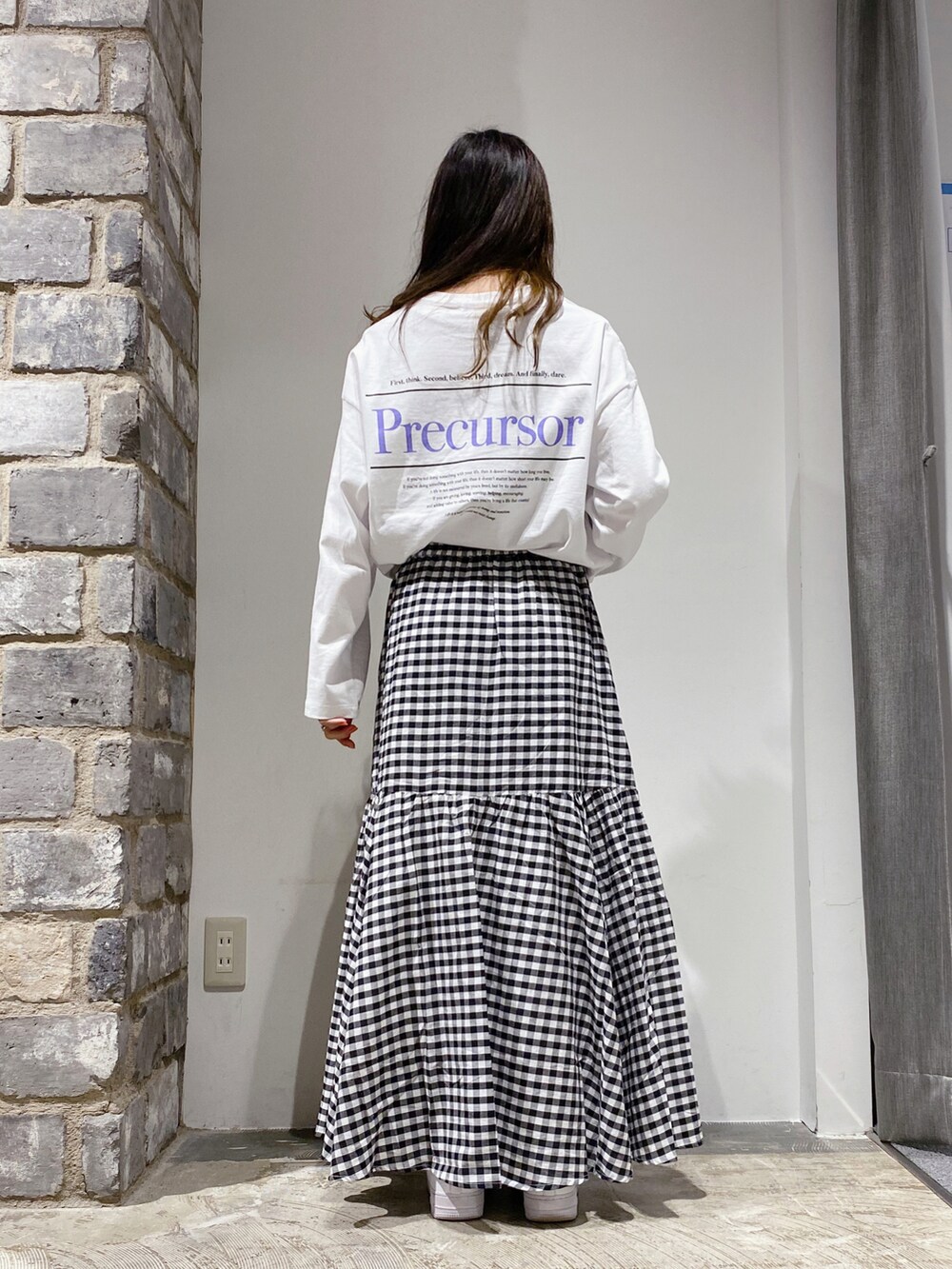 ブラック系のスカート、ホワイト系のTシャツ/カットソーを着用したレディースの春コーディネートの2枚目の写真