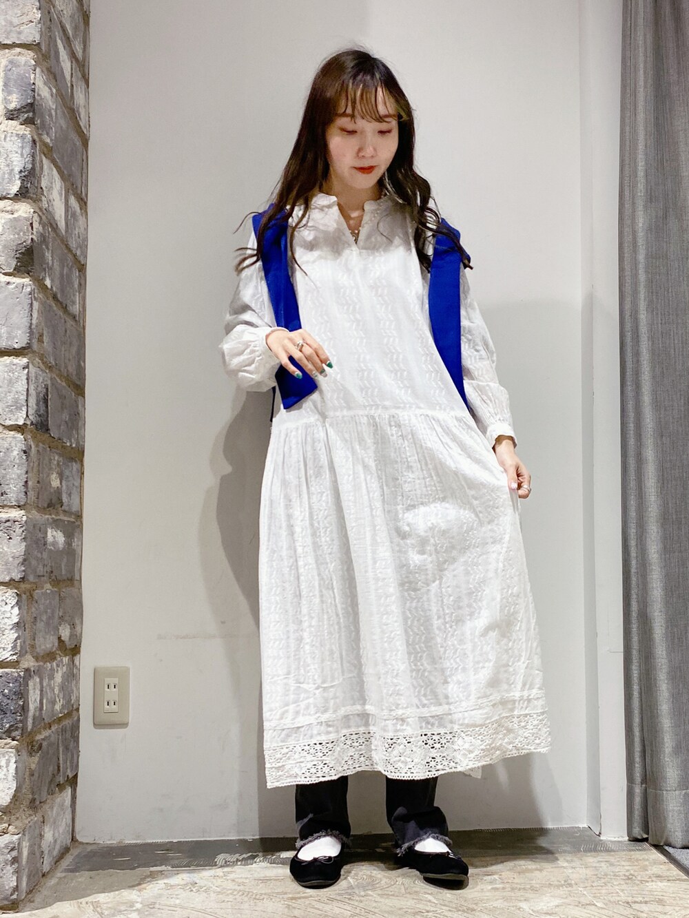 ホワイト系のワンピース、ブルー系のカーディガン/ボレロ、グレー系のデニムパンツを着用したレディースの冬コーディネートの2枚目の写真
