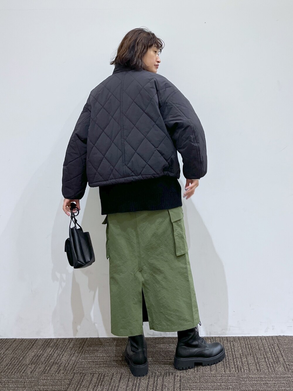 ホワイト系のトップス、ブラック系のジャケット/アウター、グリーン系のスカートを着用したレディースの秋コーディネートの3枚目の写真