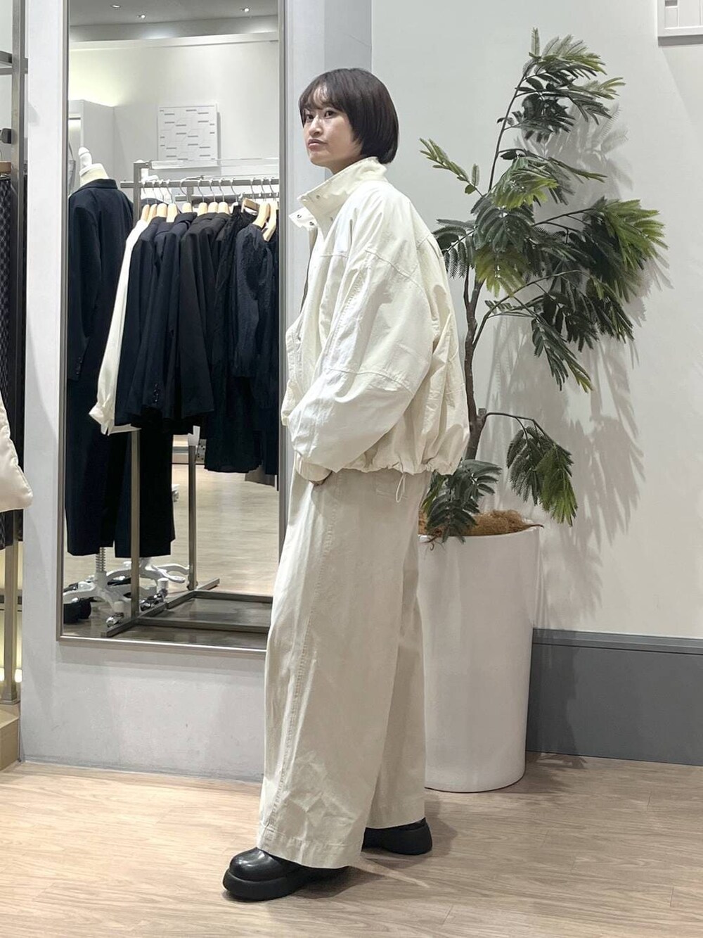 ホワイト系のナイロンジャケット、ホワイト系のデニムパンツ、ブラック系のショルダーバッグを着用したレディースの冬コーディネートの3枚目の写真