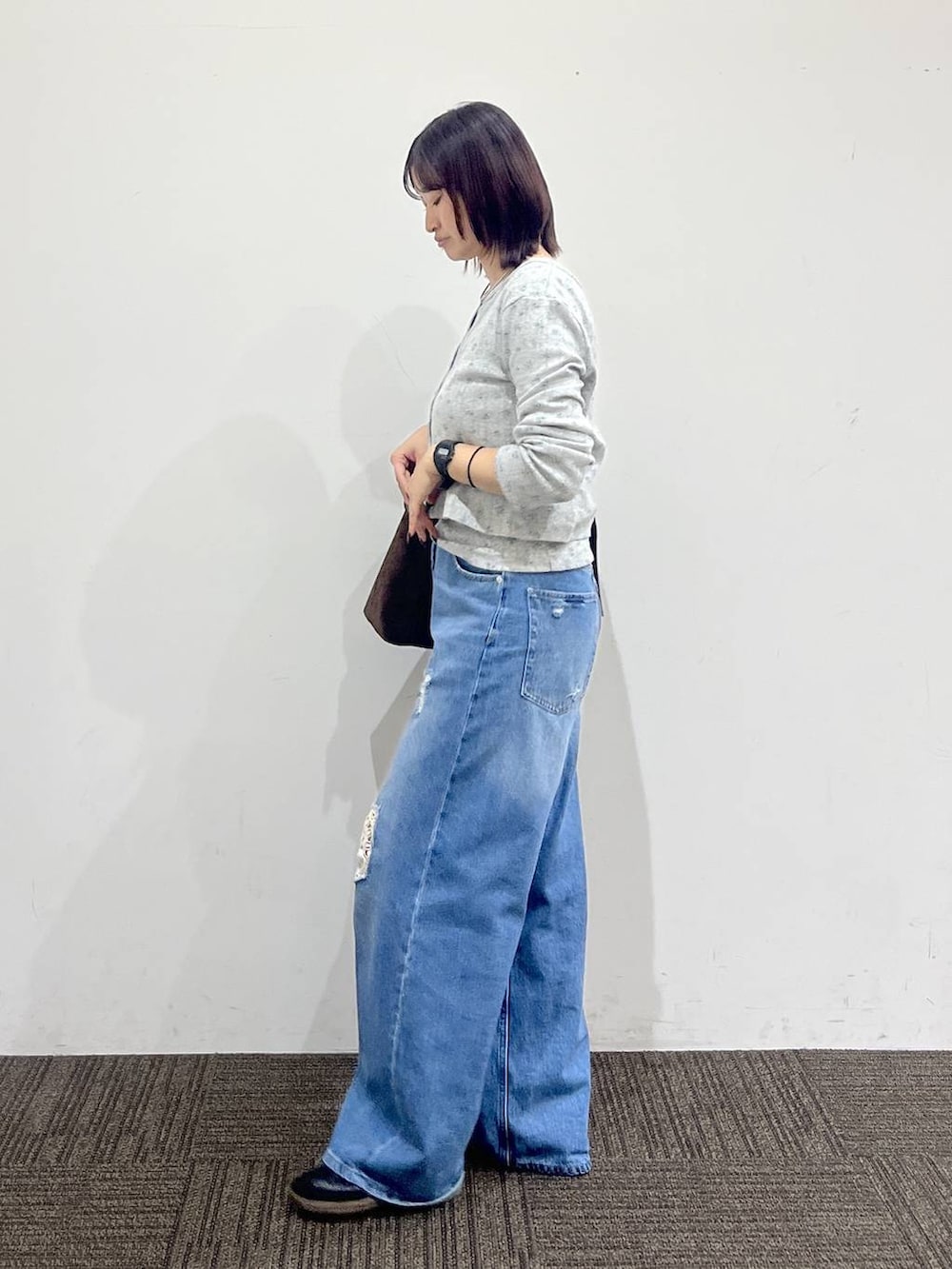 グレー系のTシャツ/カットソー、ブラウン系のショルダーバッグ、ブルー系のデニムパンツを着用したレディースの秋コーディネートの3枚目の写真