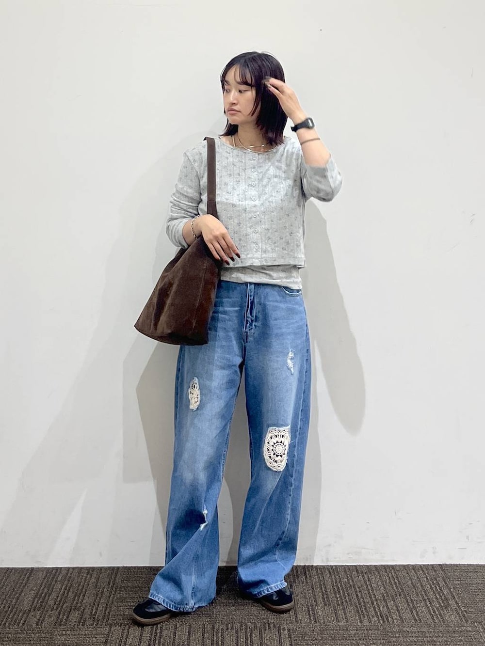 グレー系のTシャツ/カットソー、ブラウン系のショルダーバッグ、ブルー系のデニムパンツを着用したレディースの秋コーディネートの2枚目の写真