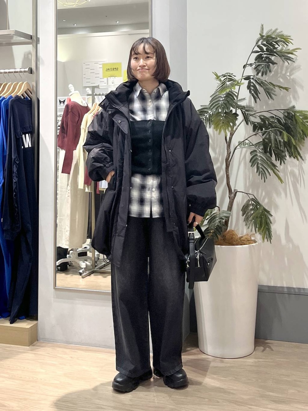 ブラック系のブーツ、ブラック系のショルダーバッグ、ブラック系のデニムパンツを着用したレディースの秋コーディネートの2枚目の写真