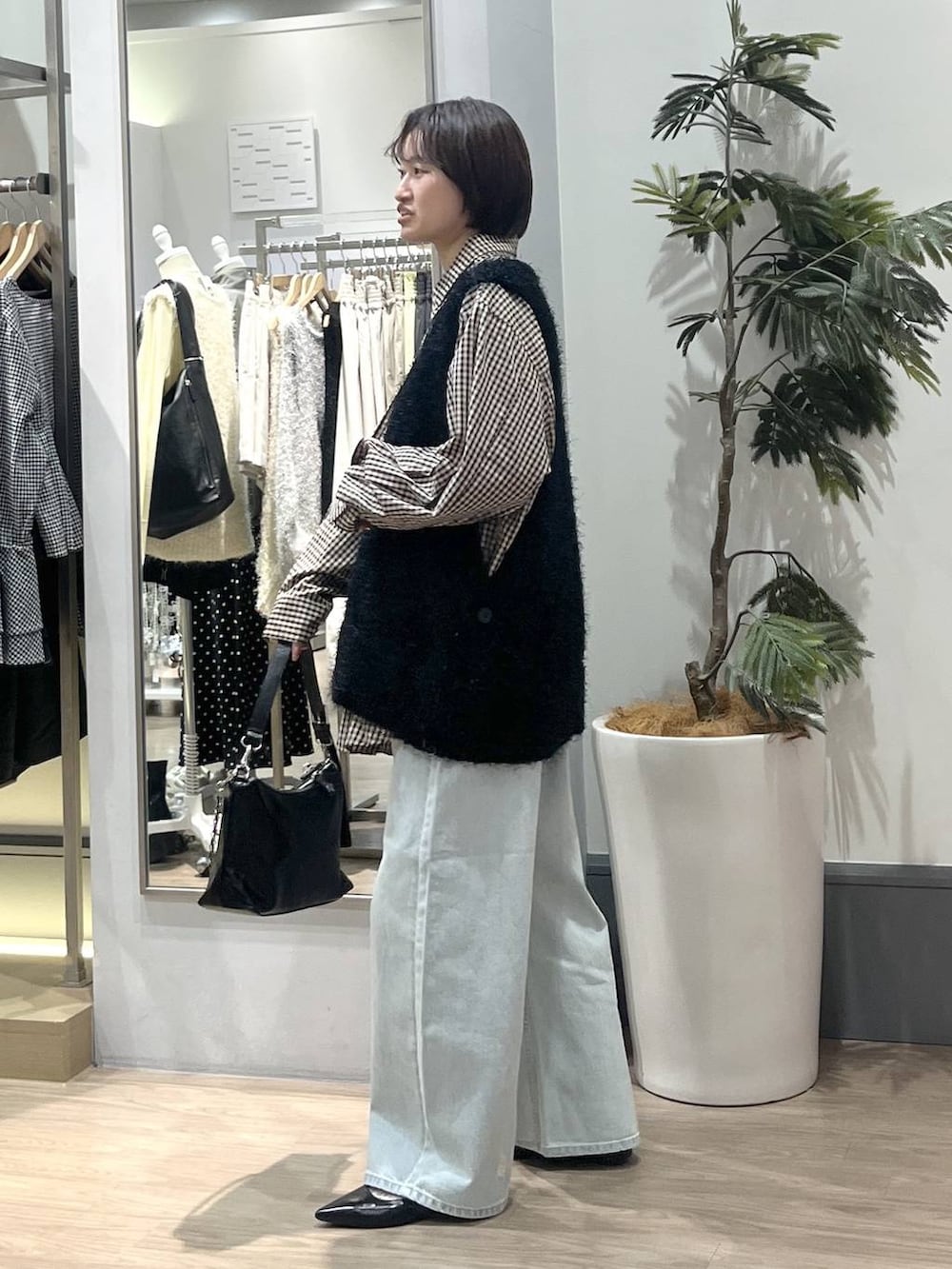 ブラック系のパンプス、ブルー系のデニムパンツ、ブラック系のショルダーバッグを着用したレディースの冬コーディネートの3枚目の写真