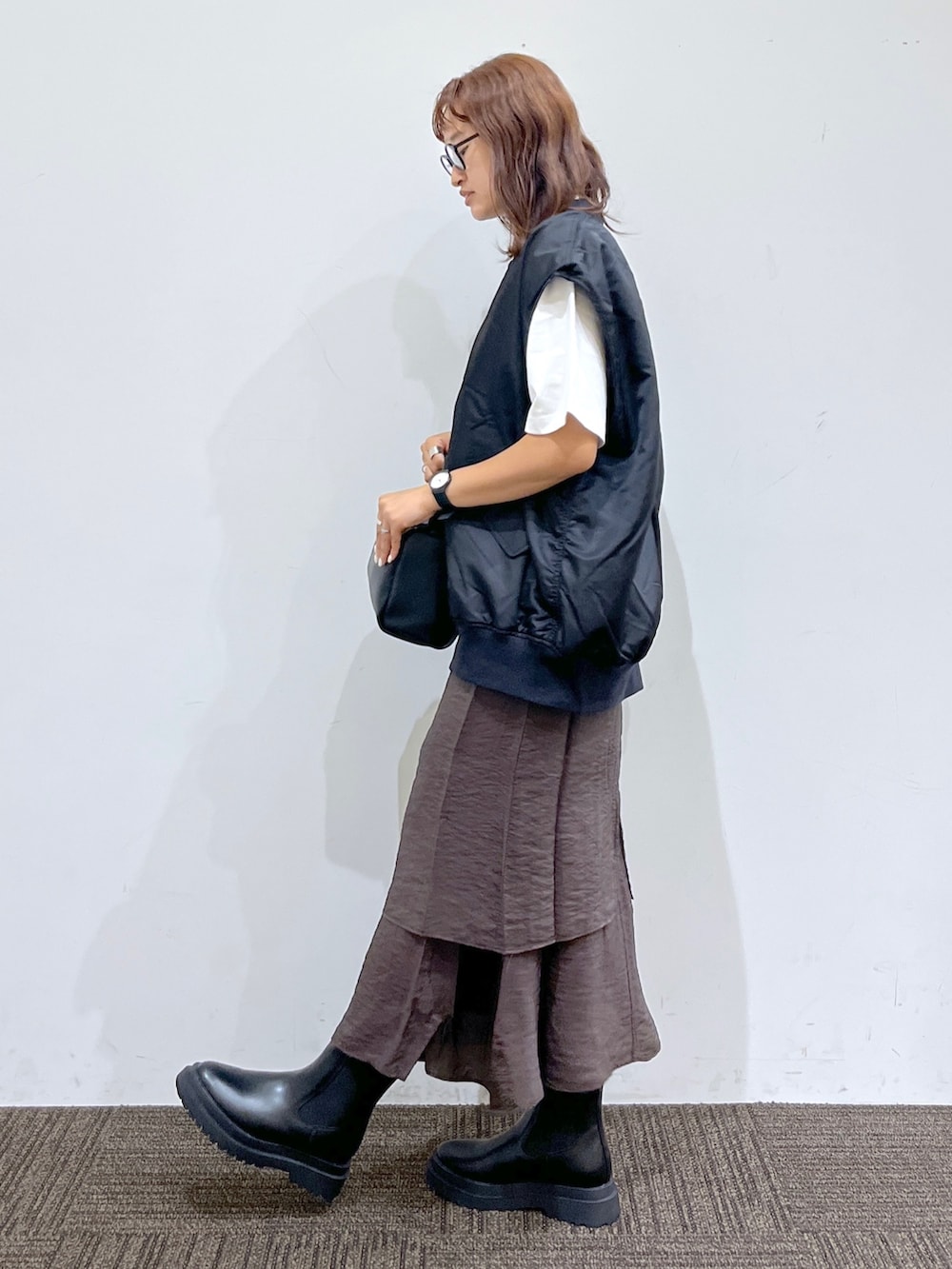 ブラック系のブーツ、ブラウン系のワンピース、ブラック系のショルダーバッグを着用したレディースの夏コーディネートの2枚目の写真