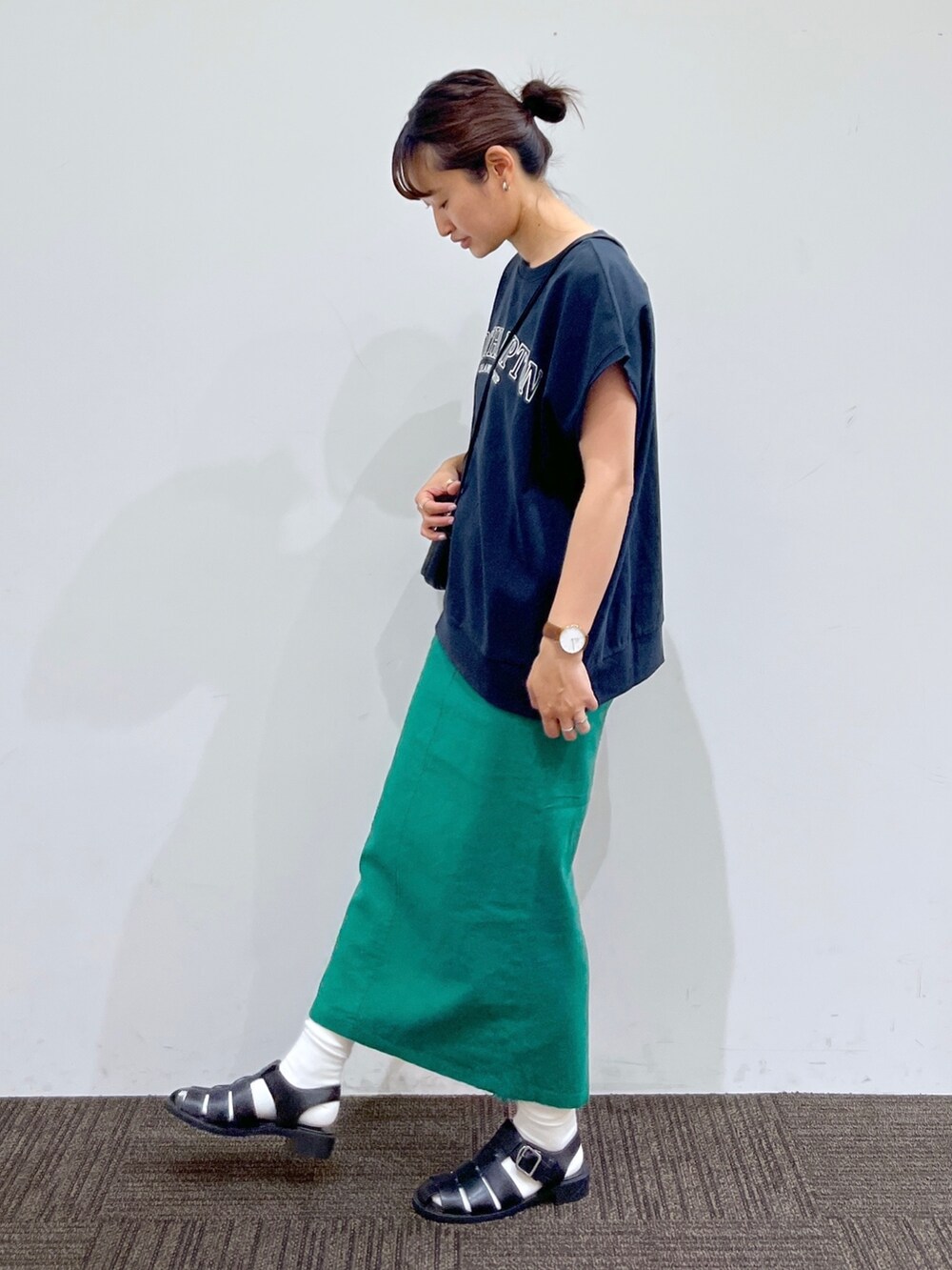 グリーン系のスカート、ブラック系のショルダーバッグ、グレー系のTシャツ/カットソーを着用したレディースの夏コーディネートの2枚目の写真