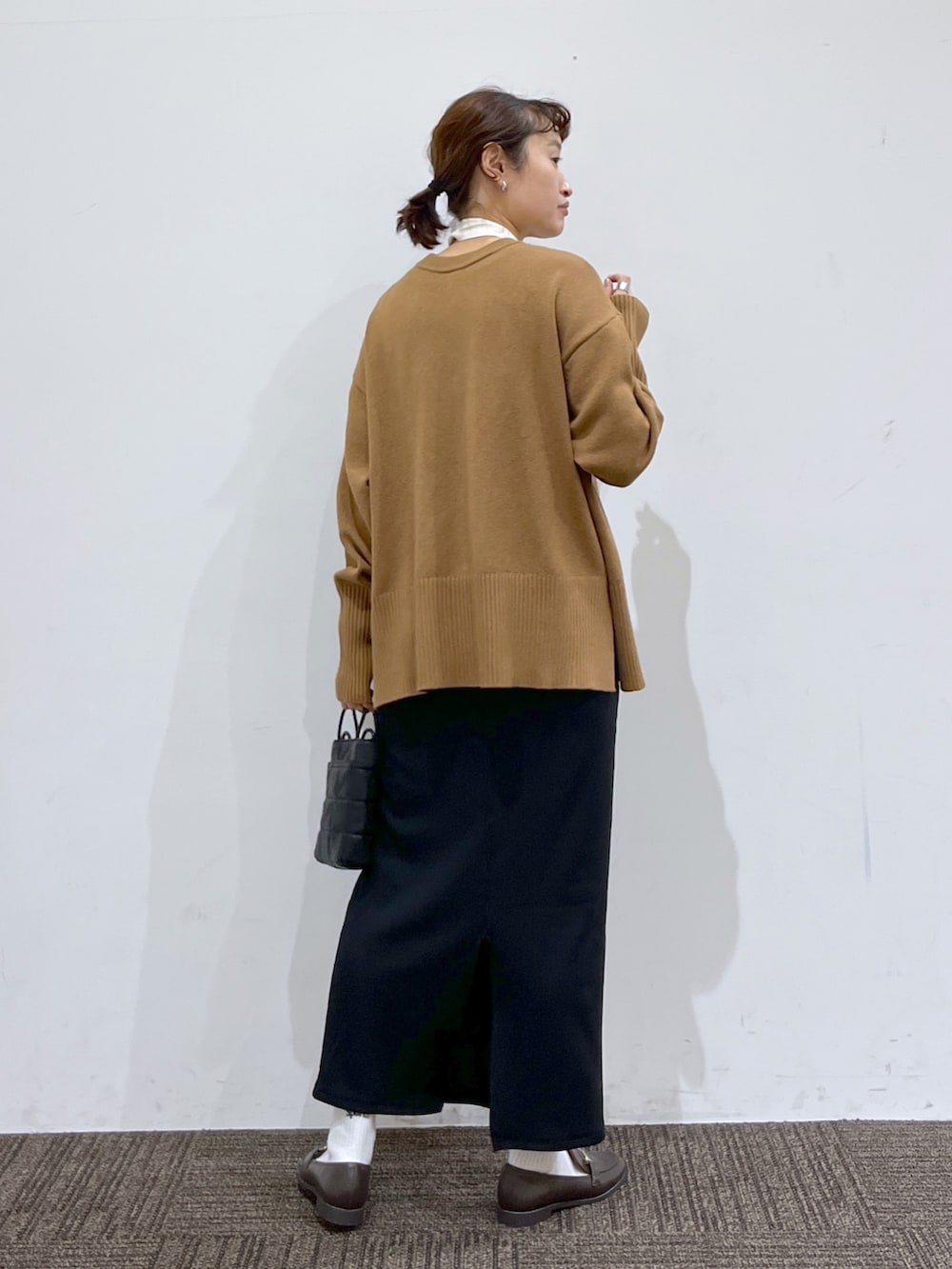 ブラック系のスカート、ホワイト系のトップス、ブラウン系のニット/セーターを着用したレディースの冬コーディネートの3枚目の写真