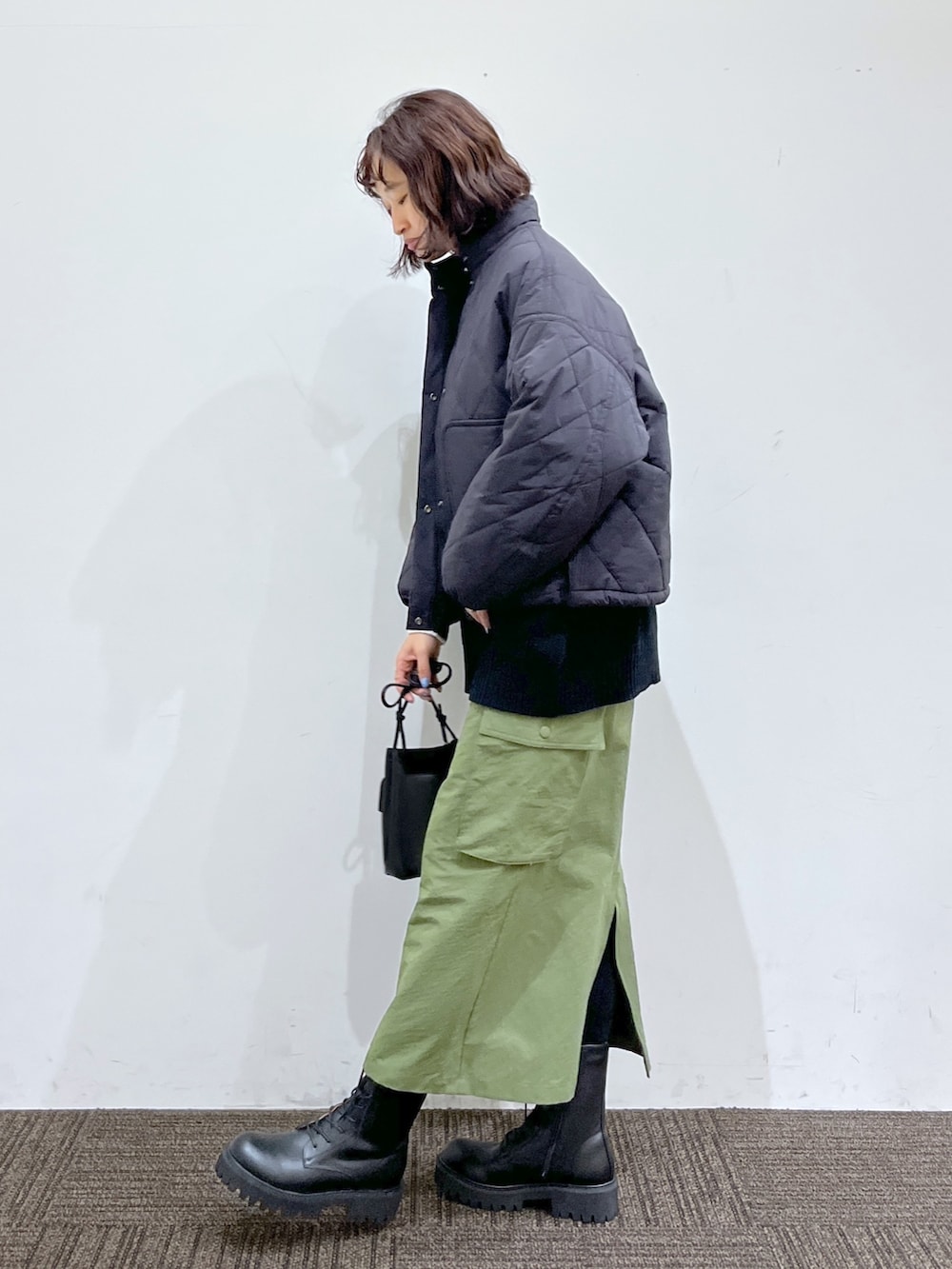 ホワイト系のトップス、ブラック系のジャケット/アウター、グリーン系のスカートを着用したレディースの秋コーディネートの2枚目の写真