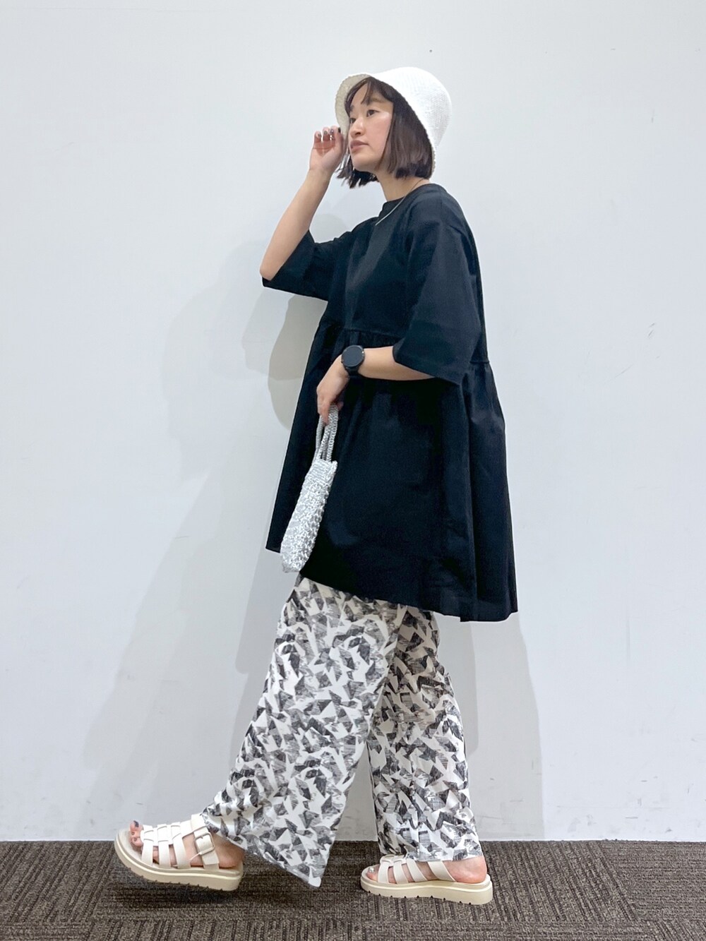 ゴールド系のバッグ、ブラック系のTシャツ/カットソー、ホワイト系のその他パンツを着用したレディースの春コーディネートの2枚目の写真