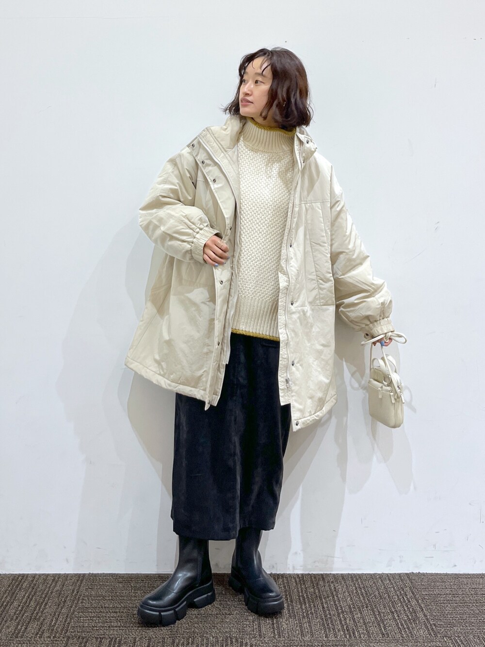 ホワイト系のショルダーバッグ、ブラック系のスカート、ホワイト系のトップスを着用したレディースの秋コーディネートの2枚目の写真