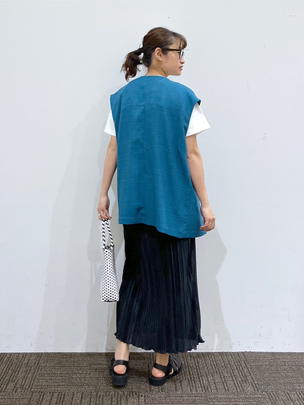 ブラック系のサンダル、ブラック系のスカート、ブラック系のかごバッグを着用したレディースの春コーディネートの3枚目の写真