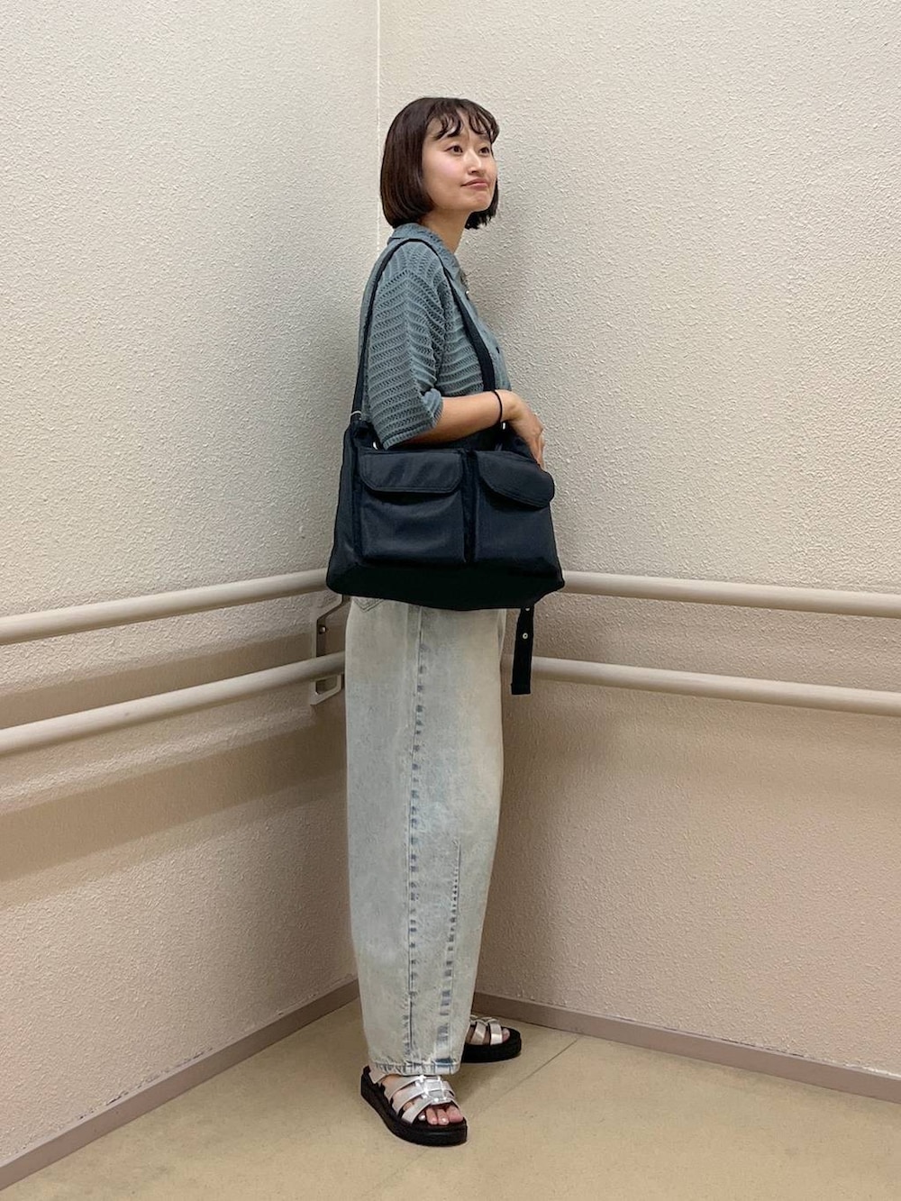 ブルー系のデニムパンツ、グリーン系のニット/セーター、シルバー系のスニーカーを着用したレディースの夏コーディネートの3枚目の写真